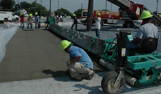 Crew from Z-Con finish off a section of pervious concrete and prepare to cover while the concrete cures. Pervious concrete permits rain to pass through the pavement and directly into the soil.